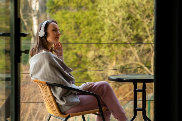 Une femme détendue avec des écouteurs respire de l'air frais médite écoute de la musique sur la terrasse de la maison