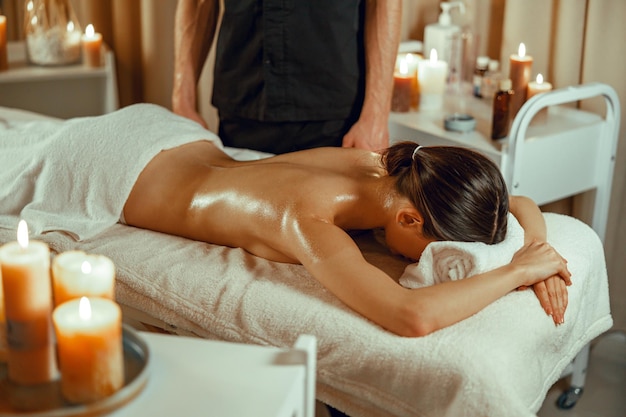 Femme détendue à moitié nue prête pour un massage du dos au spa de beauté