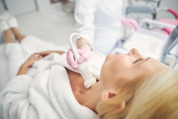 Femme détendue portant un peignoir tout en faisant un examen de santé dans une armoire moderne