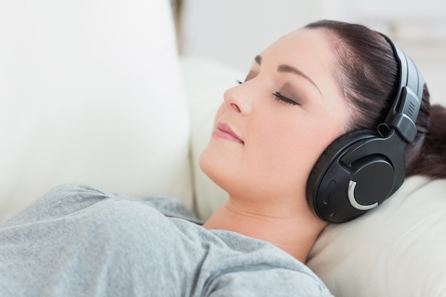 Femme détente allongée sur le canapé et écouter de la musique