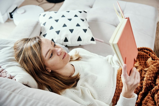 Femme détente sur canapé et livre de lecture