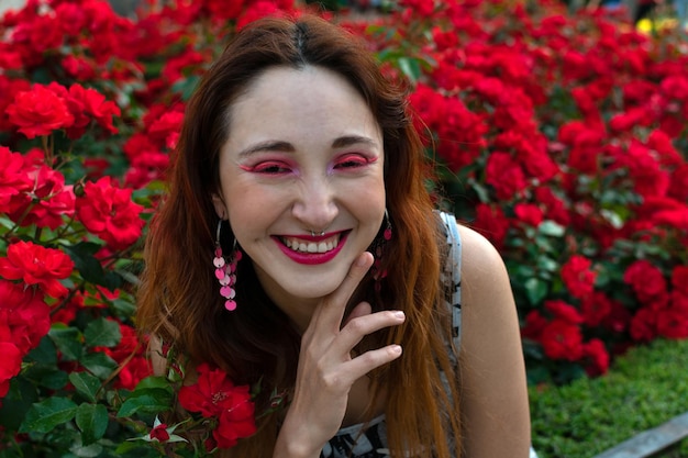 Une femme devant des fleurs rouges dans un jardin