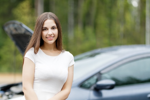 Femme devant sa voiture voiture cassée