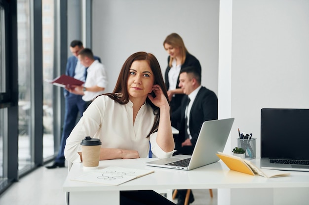 Femme devant ses collègues Groupe de personnes en tenue officielle qui se trouve à l'intérieur du bureau