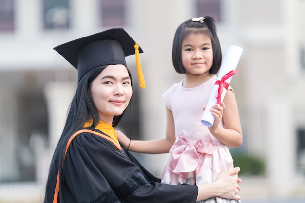 Femme diplômée avec petite fille le jour de sa remise des diplômes