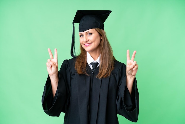 Femme diplômée de l'université d'âge moyen sur fond isolé montrant le signe de la victoire avec les deux mains