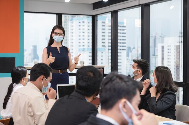 Femme De Direction Montrant Les Pouces Vers Le Haut Avec Propose La Politique De L'entreprise Sur Le Port D'un Masque Facial En Entreprise Lors De La Réunion