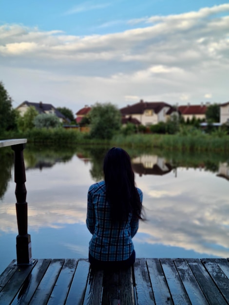 Une femme à distance sociale est assise seule au bord d'un lac pendant le coucher du soleil Dépression solitude et inquiétudes