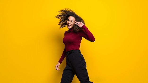 Femme dominicaine, à, cheveux bouclés, sauter, sur, mur jaune