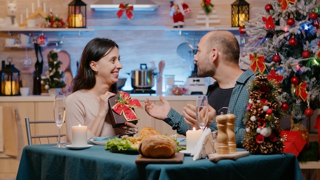 Femme donnant une boîte à un homme tout en profitant du dîner de Noël