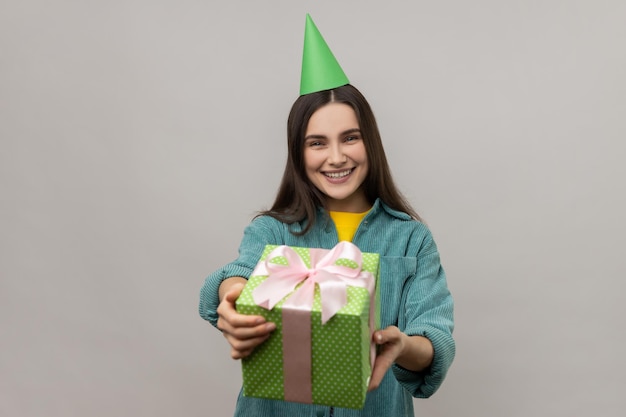 Femme donnant un cadeau vert à l'appareil photo et souriant partageant un cadeau de vacances félicitant pour son anniversaire