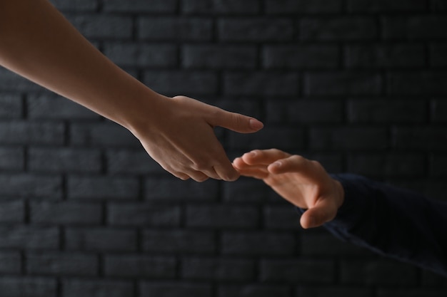 Femme donnant la main à l'homme déprimé sur fond sombre. Concept de prévention du suicide