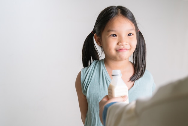 Femme donnant à sa fille une bouteille de lait à la maison