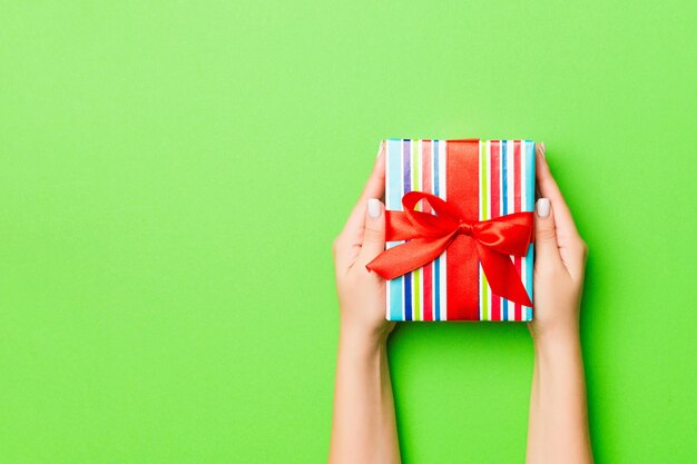 Femme donne une boîte de cadeau de Noël sur fond coloré