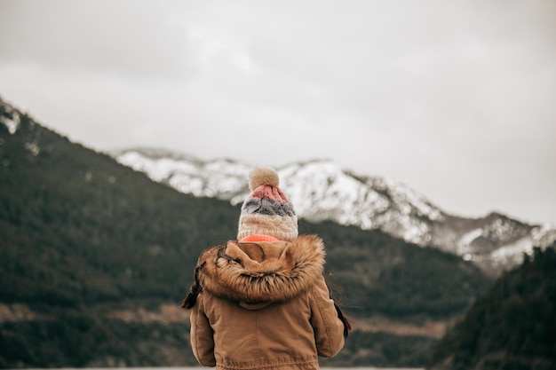 Femme de dos dans un lac avec des montagnes enneigées