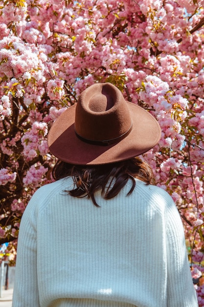 Femme de dos regardant sur l'arbre de sakura en fleurs