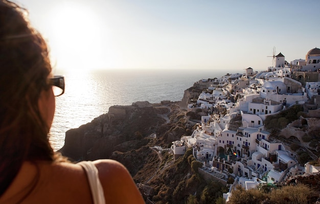 Femme de dos regardant le coucher du soleil à Santorin