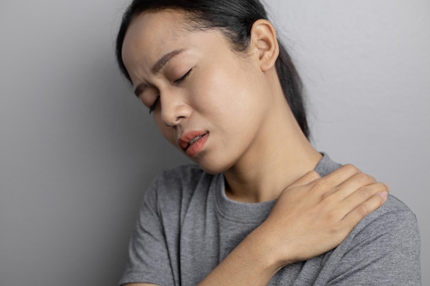 Femme avec douleur à l'épaule. Jeune femme souffrant de douleur à l'épaule. Souffrant de douleur à l'épaule de la femme.