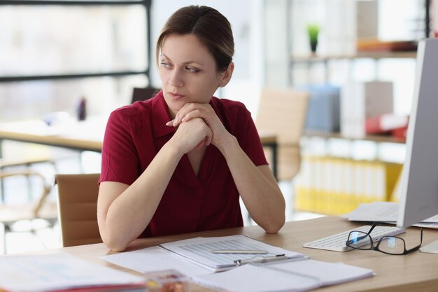 Une femme doutante pense au travail en détournant les yeux au bureau