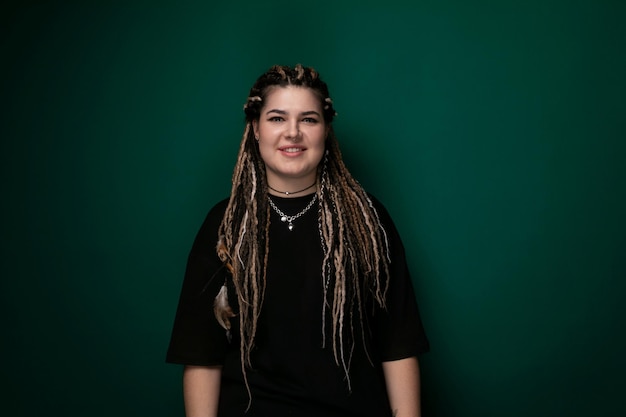 Une femme avec des dreadlocks devant un mur vert