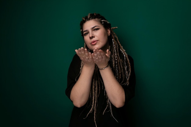 Une femme avec des dreadlocks devant un mur vert