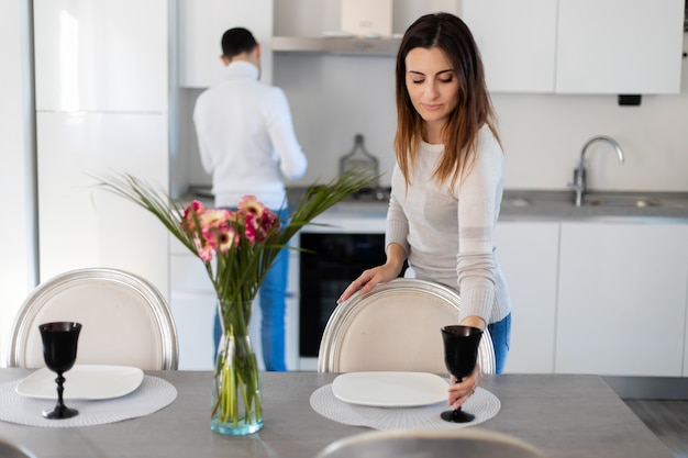 Femme dressant la table pendant que son petit ami cuisine