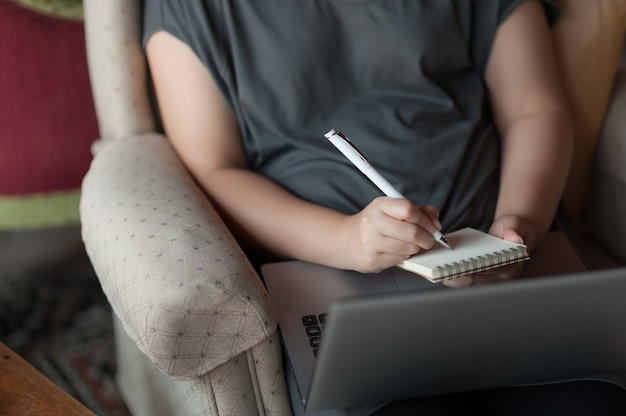 Femme droitier écrivant sur un petit bloc-notes