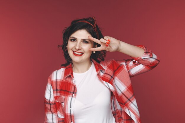 Femme drôle dans un chemisier à carreaux rouge posant dans un studio.