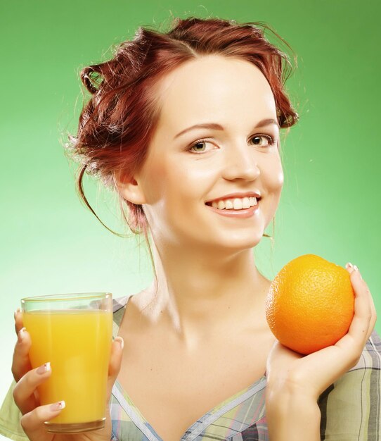 Femme avec du jus d'orange sur fond vert