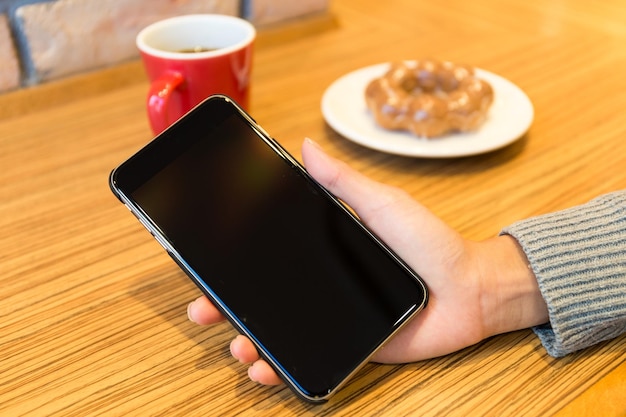 Femme avec un éboulis vierge de téléphone portable au café