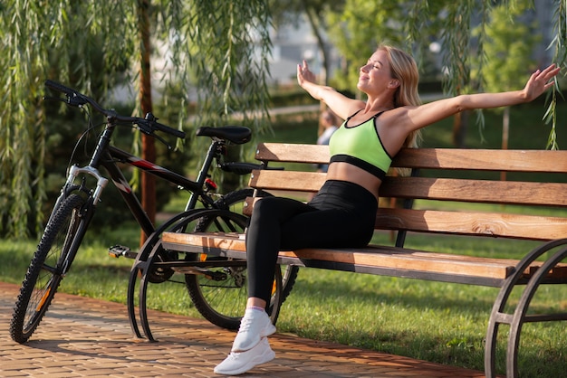 Femme écartant les bras et assise sur un banc