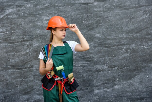 Femme avec échantillon de couleur. Elle en combinaison et casque posant sur fond abstrait