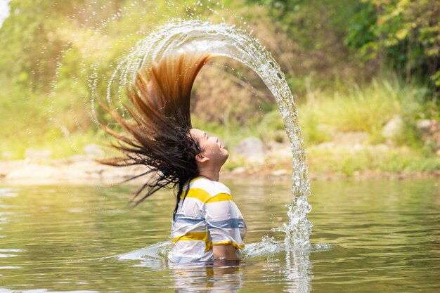 Une femme éclaboussant de l'eau tout en jetant ses cheveux dans le lac