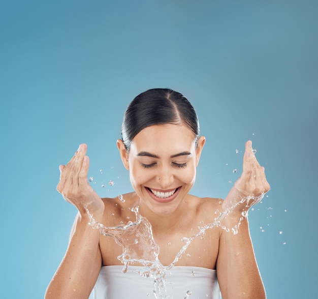 Femme éclaboussures d'eau nettoyage du visage et douche de bien-être et soins de la peau éclatants sur fond de studio de maquette Bonne jeune fille beauté du visage goutte d'eau et lavage du visage corps naturel et soins personnels