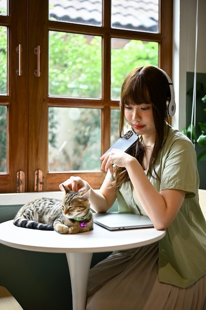 Une femme écoutant de la musique dans ses écouteurs et se reposant avec son chat