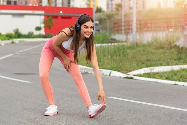 Femme écoutant de la musique, faisant des exercices d'entraînement dans la rue.