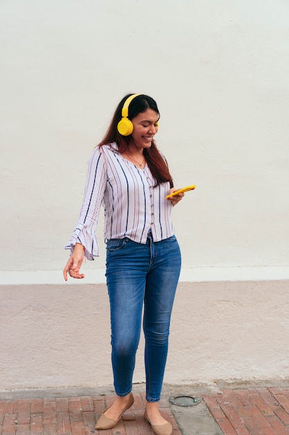 Femme écoutant de la musique sur son téléphone portable en se tenant debout dans la ville