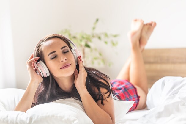 Une Femme écoute De La Musique Avec Des écouteurs Allongée Sur Le Lit Un Jour D'été.