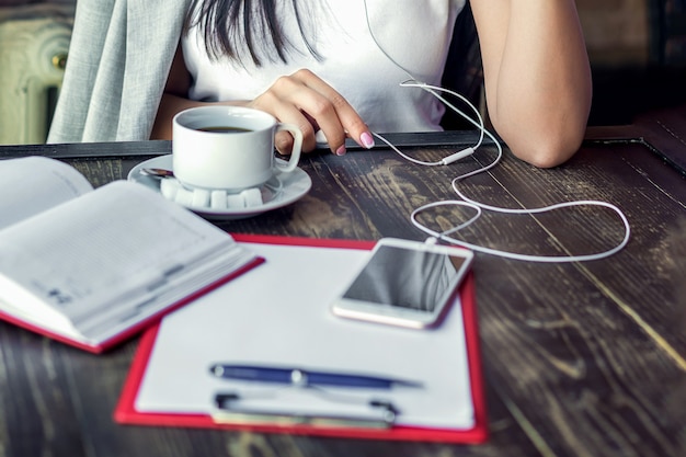 La femme écoute de la musique avec des écouteurs avec une tasse de café dans le café.