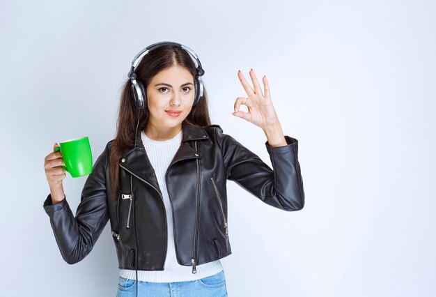 femme avec des écouteurs ayant une tasse de thé vert.