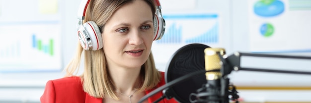 Femme avec des écouteurs devant le microphone à la conférence d'affaires en ligne de table de travail