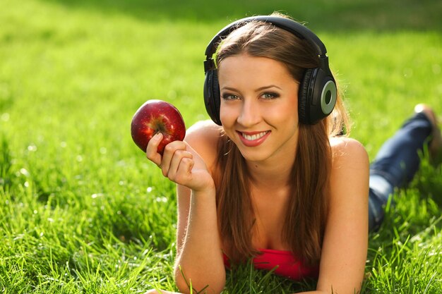 Femme avec des écouteurs écoutant de la musique sur l'herbe