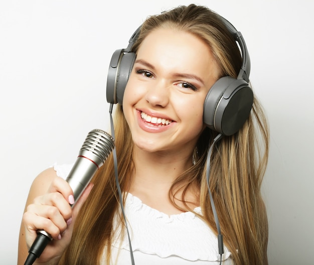 Femme avec des écouteurs et des microphones écoutant de la musique et chantant