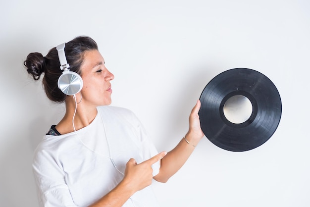 Une femme avec des écouteurs pointe vers une musique de disque vinyle