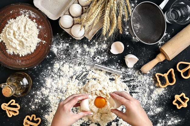 Une femme écrase un œuf à l'aide d'un couteau tout en pétrissant une pâtisserie Prise de vue en studio Vue de dessus