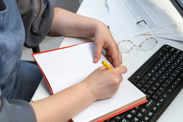 Une femme écrit dans un cahier sur le lieu de travail. Comptable au travail. Gestionnaire des tâches. Ordonnancement des tâches.