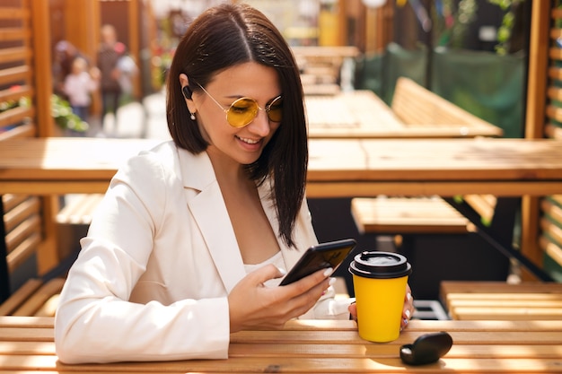 Une femme écrit des messages dans son smartphone et écoute de la musique