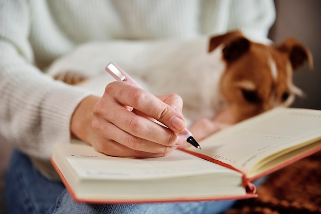 Une femme écrit des notes dans un cahier à la maison