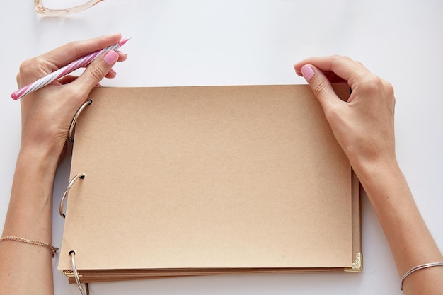 Femme écrivant sur un album en papier kraft par sa main gauche Photo conceptuelle de la journée des gauchers Maquette d'album Vue de dessus Espace de copie