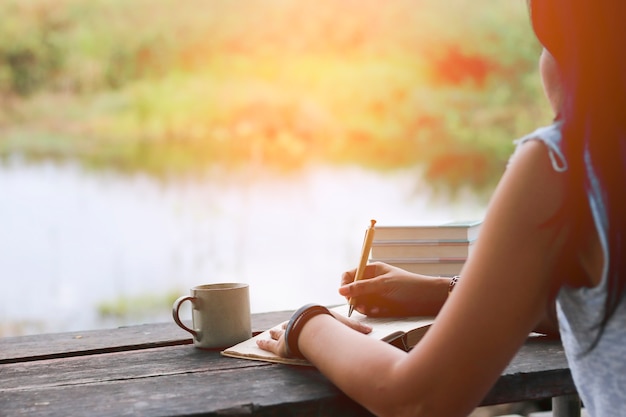 femme écrivant cahier sur la table en bois.